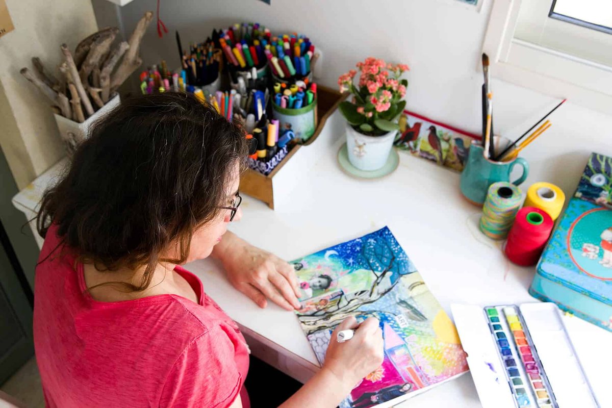 A woman at her own table, working on a visual journal page