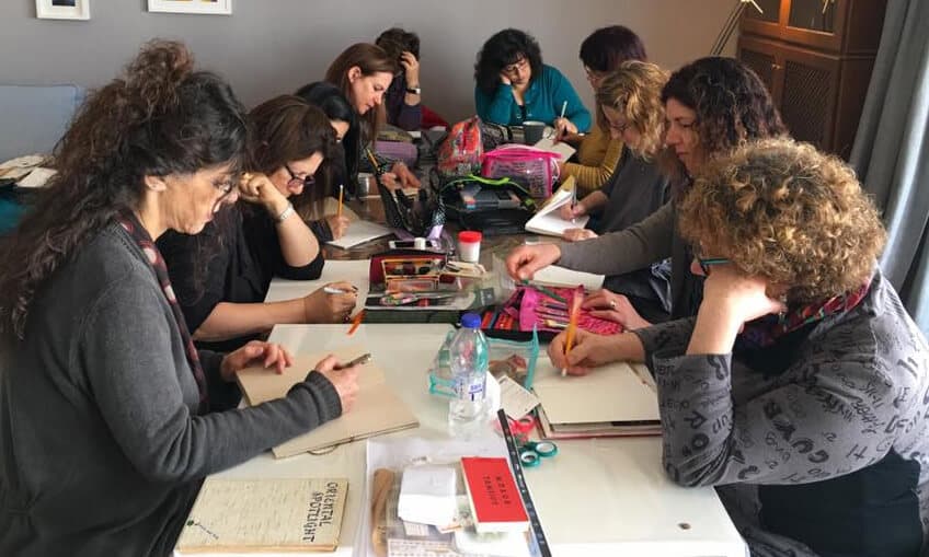 Women bent over their journals at a long table, working quietly